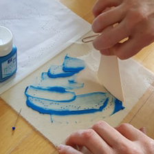 Hand stryker ut blå färg på plast med en smökniv